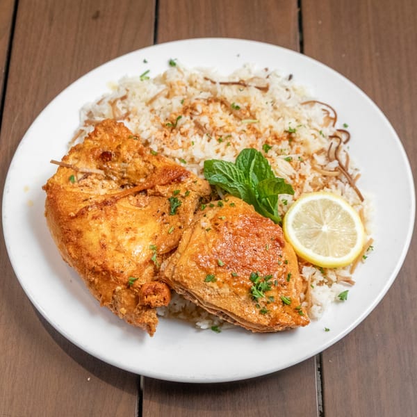 Mediterranean chicken and rice dish with lemon and mint on a white plate.