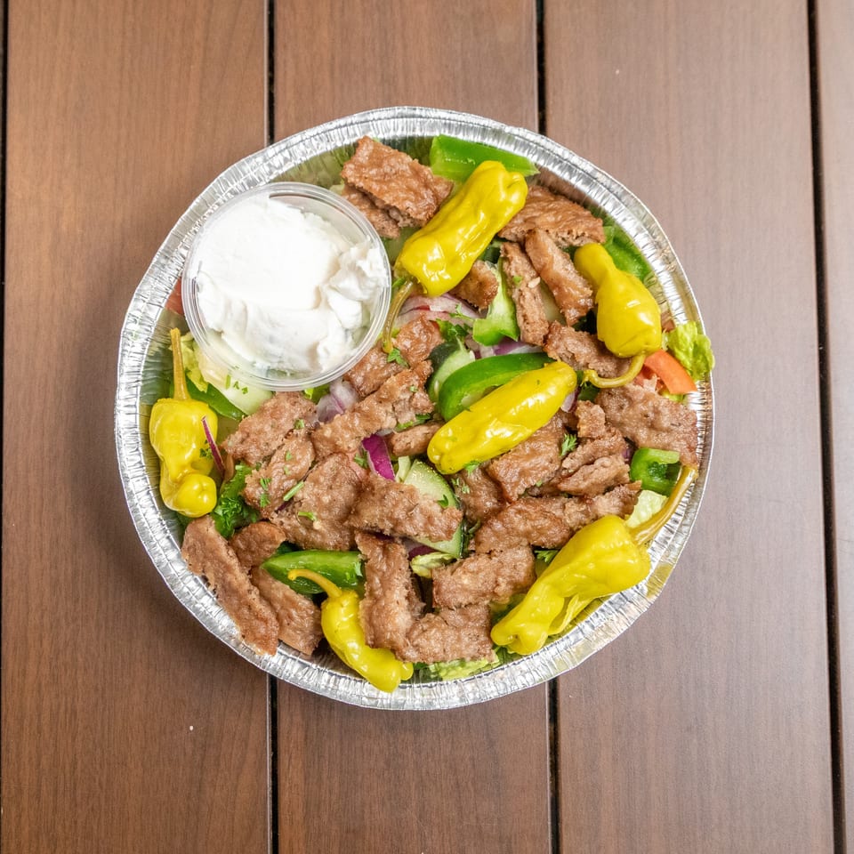 Liberty's Mediterranean Giant Grinders' gyro salad with meat, peppers, and a side of tzatziki sauce.